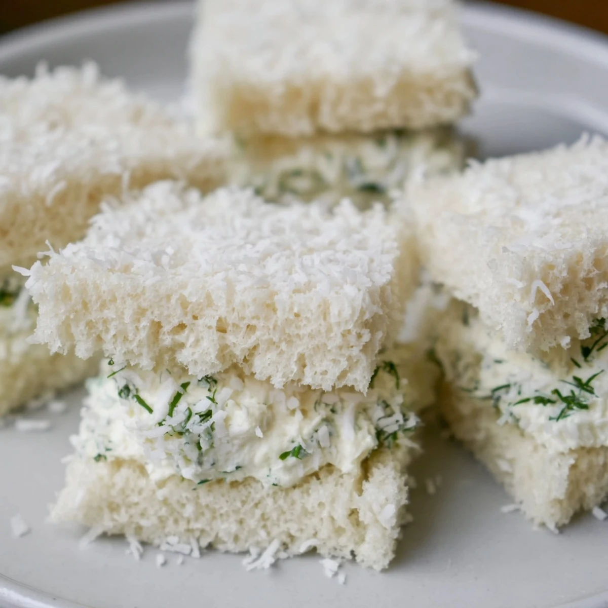 Delightful Snowball Tea Sandwich Bites, white bread rounds coated in snowy coconut, perfect for tea.