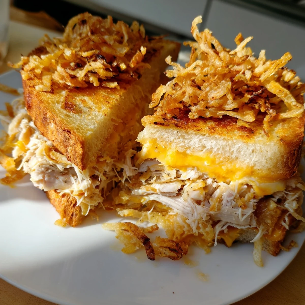 Crispy Shallot Chicken Grilled Cheese, golden and oozing with melted cheese, ready to be sliced.