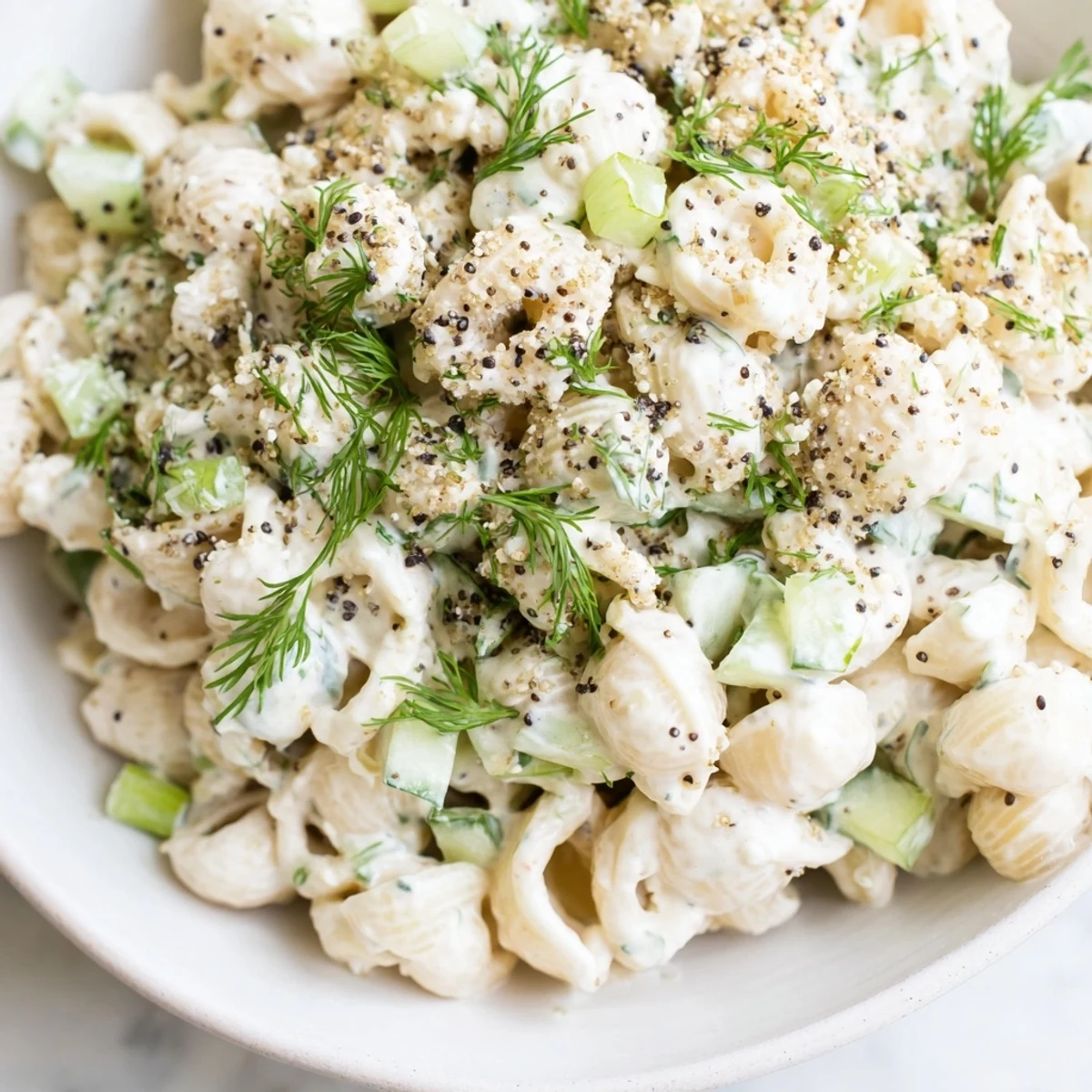 Vivid close-up of Cucumber Crunch Pasta Salad showing diced cucumbers and green onions in tangy dressing with pasta shells.