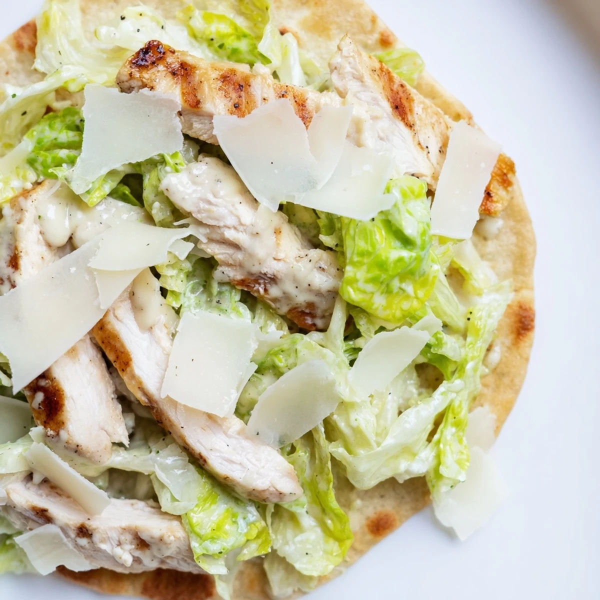 Golden-brown flatbread topped with grilled chicken, fresh romaine, and creamy Caesar dressing.