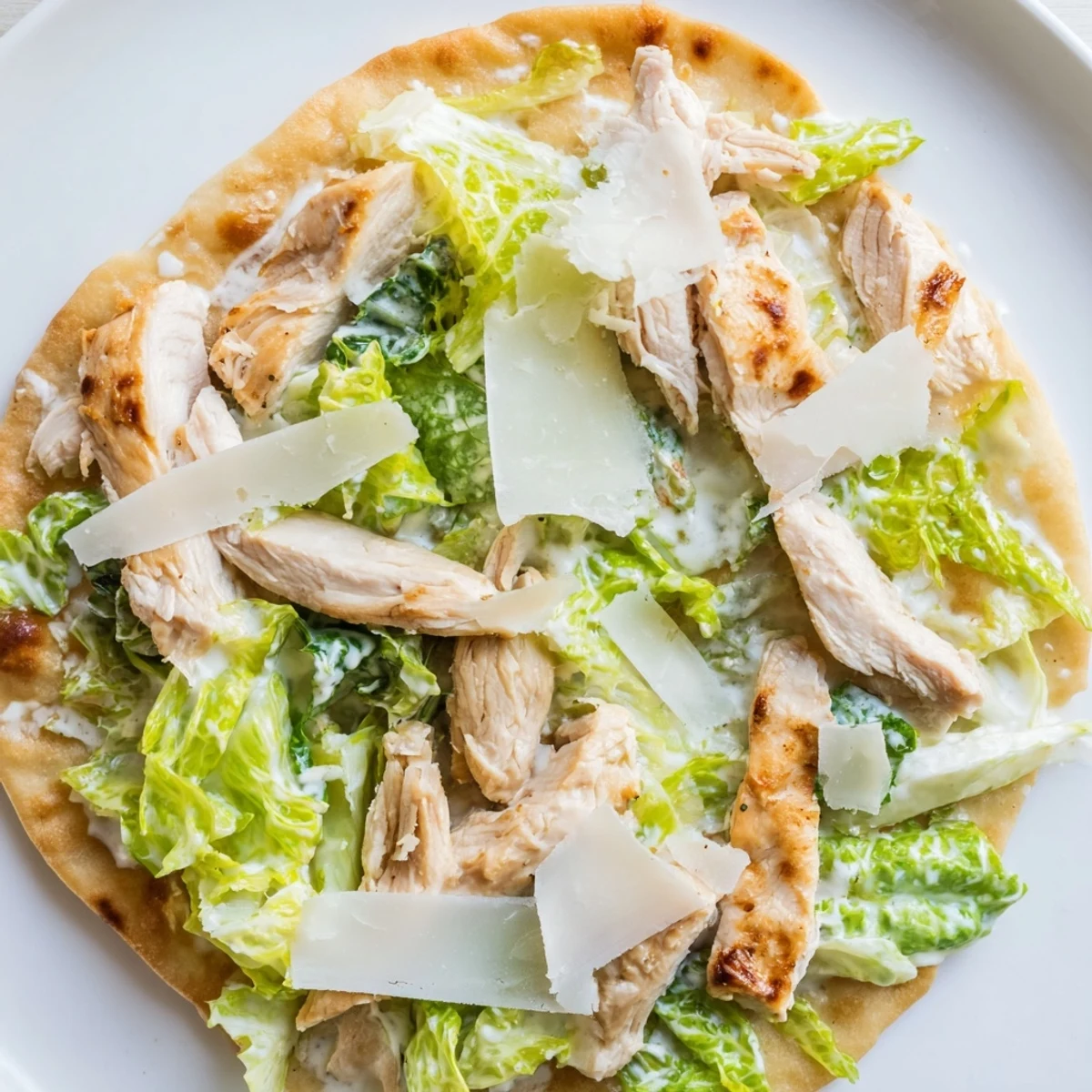 Sliced grilled Chicken Caesar Flatbread with shaved parmesan and optional cherry tomatoes.