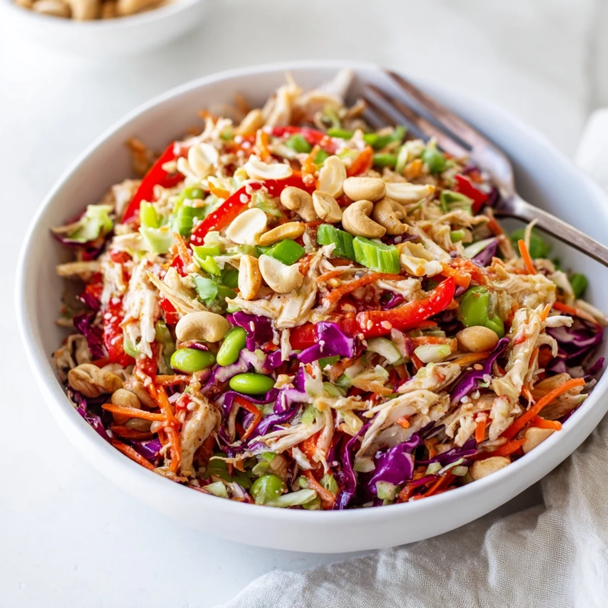 A close-up of Edamame Crunch Chicken Salad with shredded chicken, crisp cabbage, carrots, and edamame in a ginger dressing.