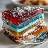 Colorful agar-agar jelly dessert in rainbow hues topped with silky coconut cream, offering a naturally dairy-free and gluten-free treat.