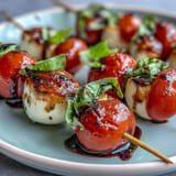 Fresh mini Caprese skewers showcasing bright tomatoes, mozzarella, and basil, drizzled.