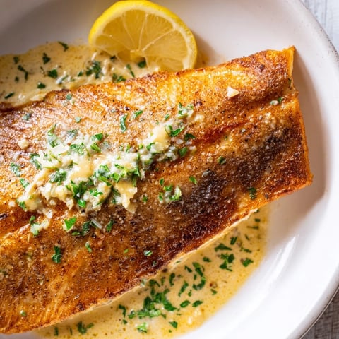 Flaky Simple Fork-Friendly Lemon-Herb Tilapia, swimming in a buttery sauce with briny capers, ready to serve.