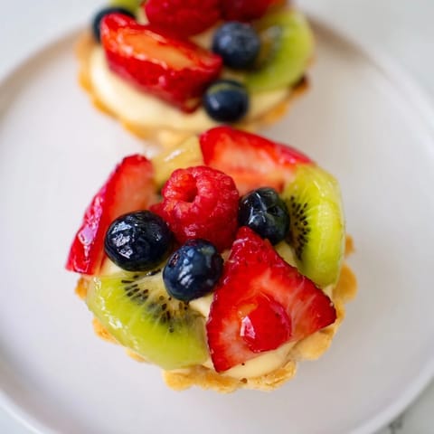 These tempting Mini Fruit Tartlets feature glossy fruits atop creamy pastry and a buttery, golden crust.