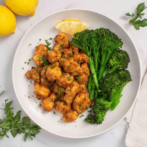 Flavorful microwave-steamed chicken and broccoli, sizzling with steam, perfect with lemon wedges.