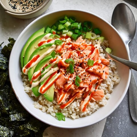 Freshly prepared Emily Mariko Salmon Rice Bowl garnished with green onions and sesame seeds, served alongside crispy roasted seaweed sheets.