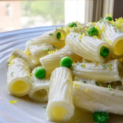 Rigatoni coated in silky Pea & Lemon Ricotta Pasta, served warm with bright lemon zest and fresh herbs on top.