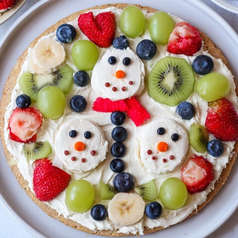 This Melting Snowman Fruit Pizza features a sweet sugar cookie crust, topped with happy, melting snowmen.
