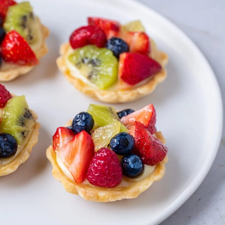 A dazzling circle of vibrant fruit crowns each Mini Fruit Tartlet, ready for a delicious dessert experience.
