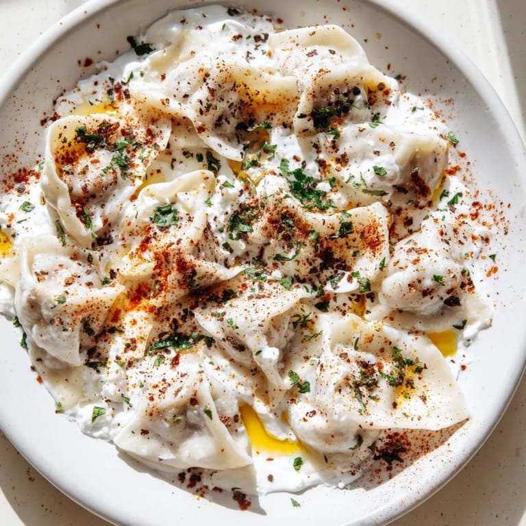 Freshly cooked, tender Turkish Cheesy Manti: small cheese dumplings garnished with red pepper flakes.