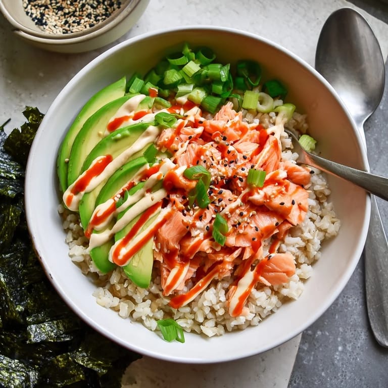 Freshly prepared Emily Mariko Salmon Rice Bowl garnished with green onions and sesame seeds, served alongside crispy roasted seaweed sheets.