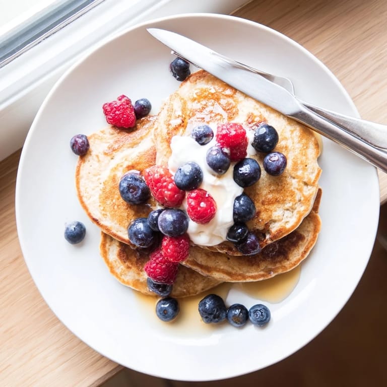 A fork lifts a fluffy, golden Cottage Cheese Pancake from a warm stack, revealing the moist, cake-like interior.