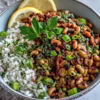 Vegetarian Hoppin John served over fluffy white rice, topped with fresh parsley and sliced green onions for a classic Southern meal.