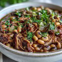 Steaming bowl of Classic New Years Black-Eyed Peas served over fluffy white rice with a side of collard greens and golden cornbread.