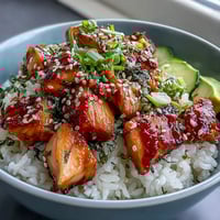 Spicy mayo salmon rice bowl with tender salmon cubes, creamy spicy mayo, crisp cucumber, and sesame seeds over fluffy rice.