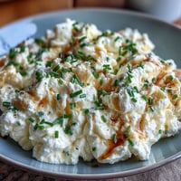 Creamy scrambled eggs with cottage cheese, garnished with fresh chives and black pepper.  